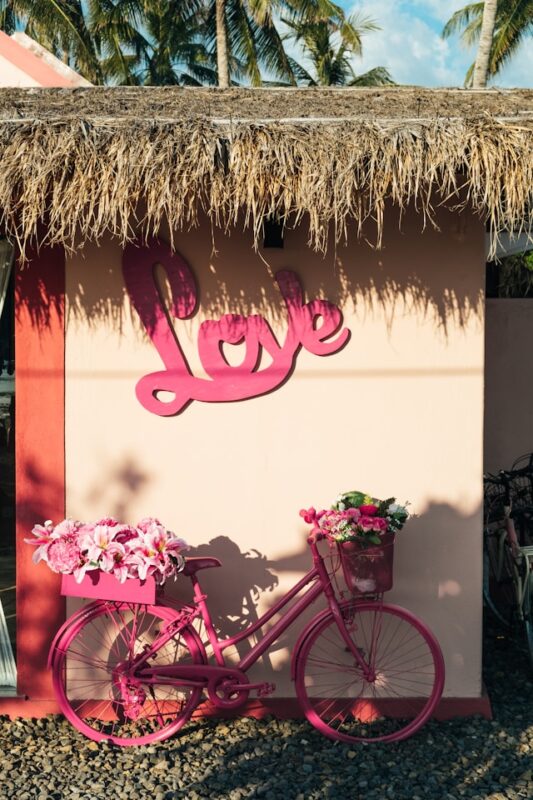 love sign on outdoor wall with pink bike and flowers