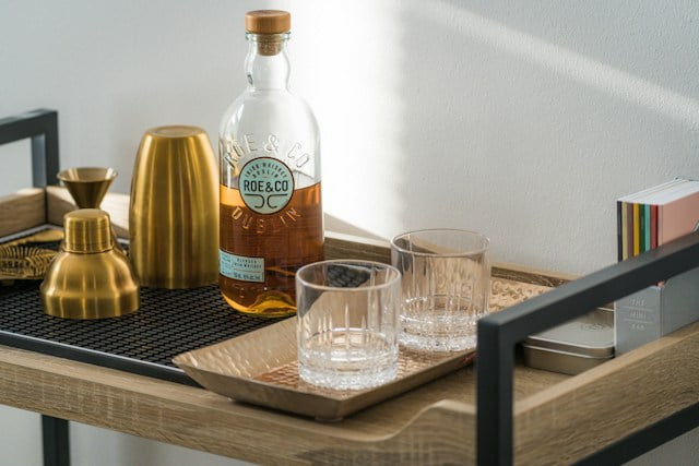 Modern style bar cart topped with glasses and gold shaker tins