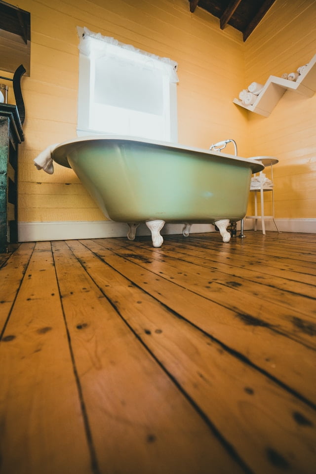 western bathroom with wooden floor and green bath tub