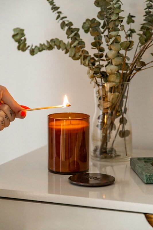 hand lighting an orange candle