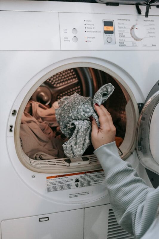 cleaning your messy house by loading laundry into a dryer