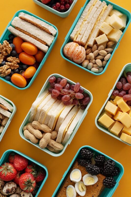 various lunch boxes filled with colorful food on a yellow background