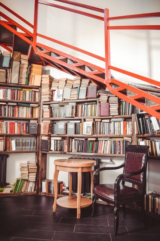 bookcase filled with books under orange staircase