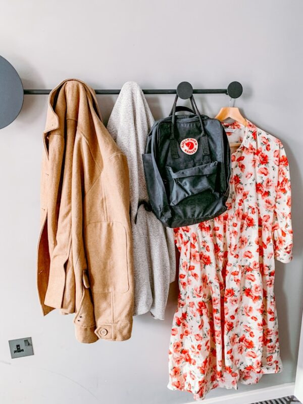 back-to-school prep idea for entry way, clothes and backpack hanging on wall hooks