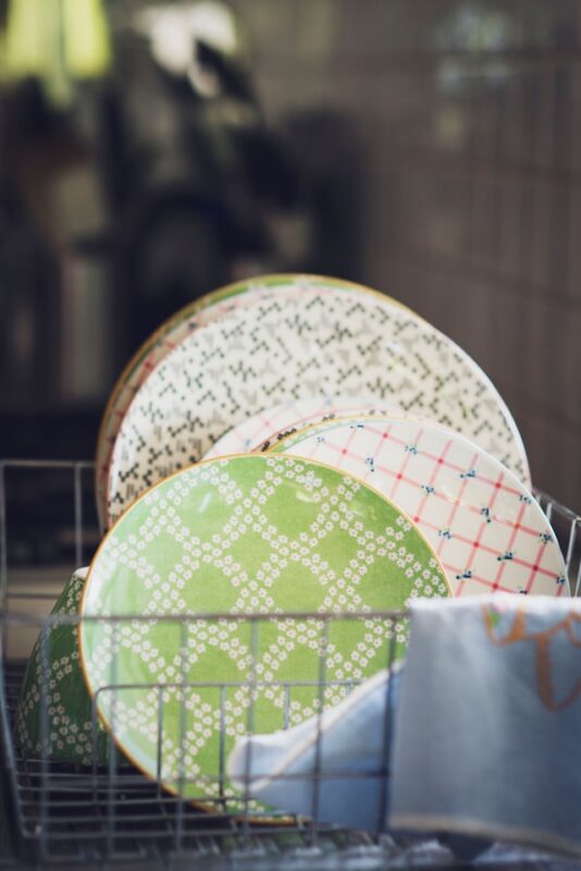 clean green and patterned dishes sitting in a wire drying rack