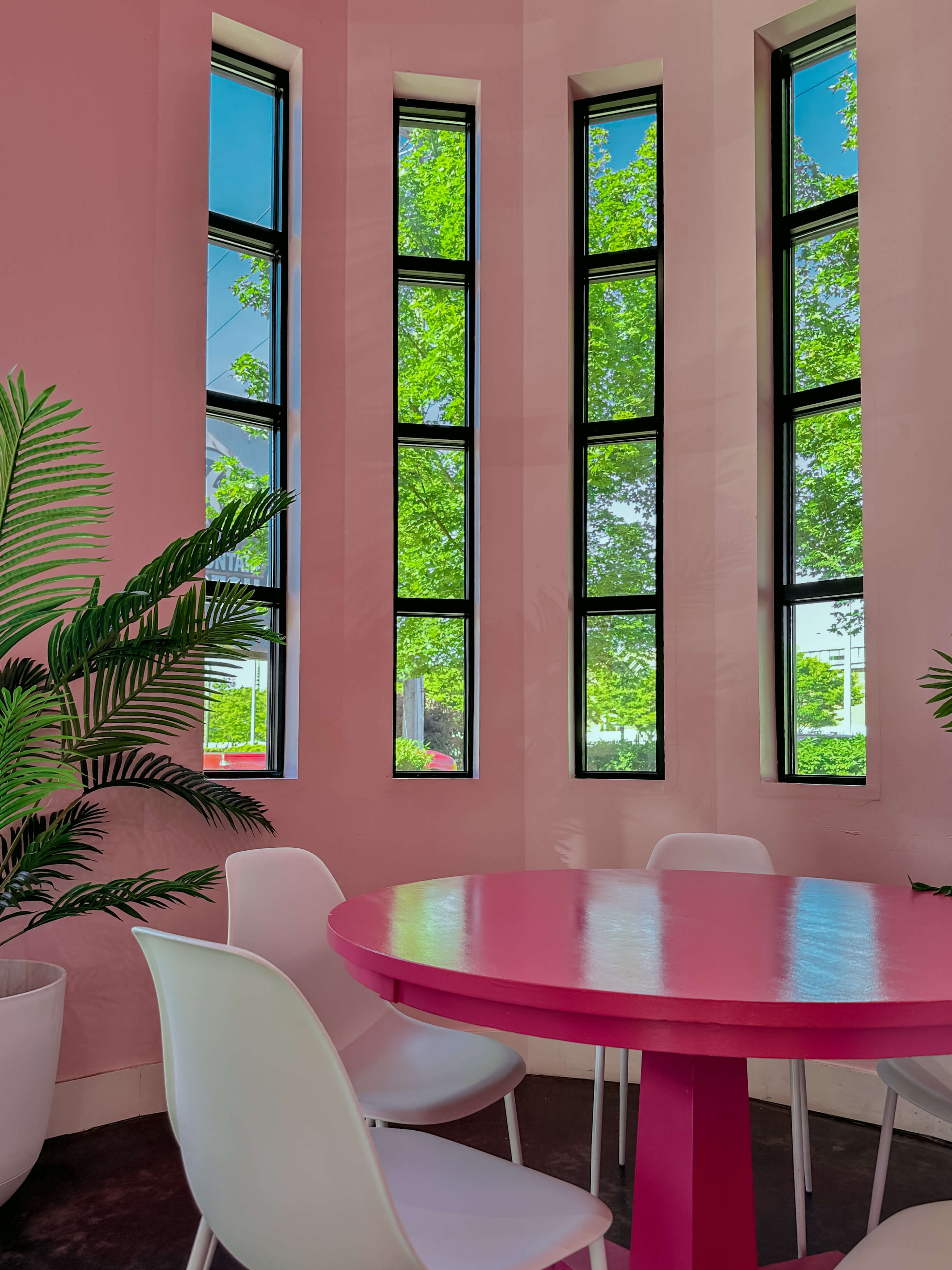 bright pink maximalist decor room with table and white chairs