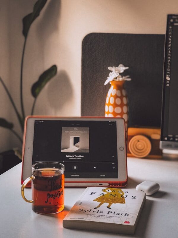 iPad playing a song with book and glass cup of tea