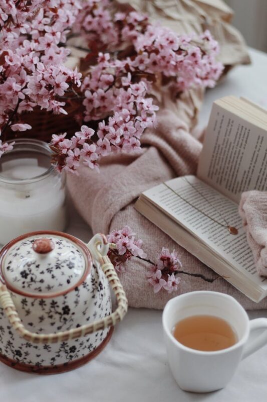 cozy reading nook with pink flowers, teapot, and white candle 