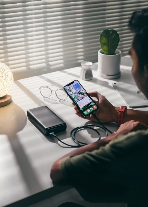 person in green shirt charging their phone with a portable charger