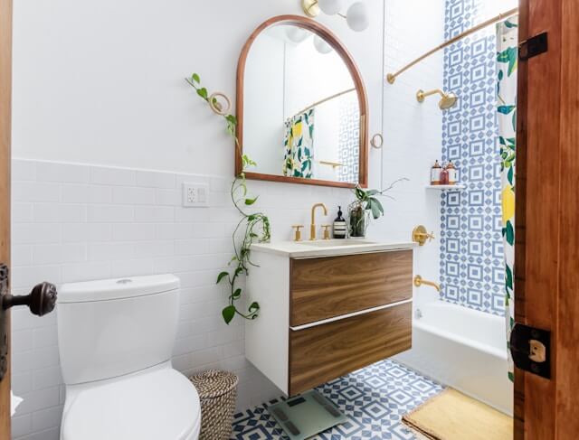 arched bathroom mirror with vines and wooden cabinets 