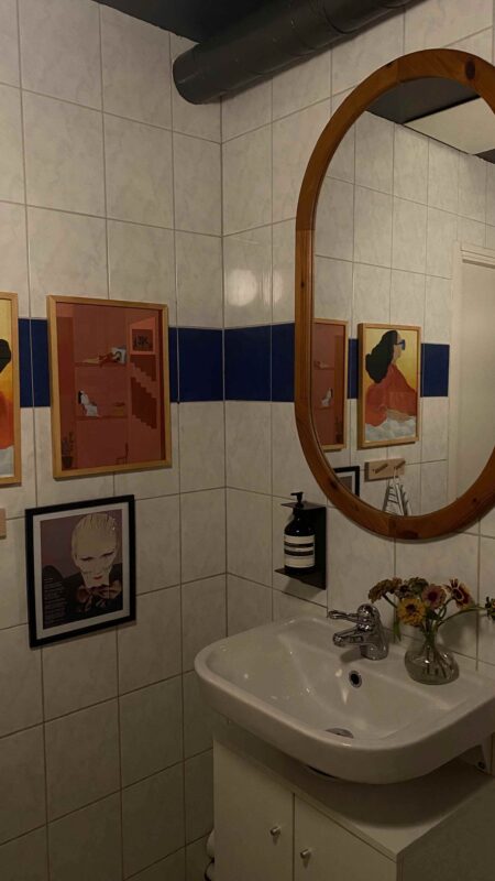 oval-shaped bathroom mirror with thick wooden frame on tiled wall 