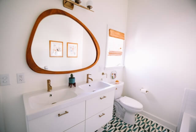 asymmetrical wooden-framed round bathroom mirror